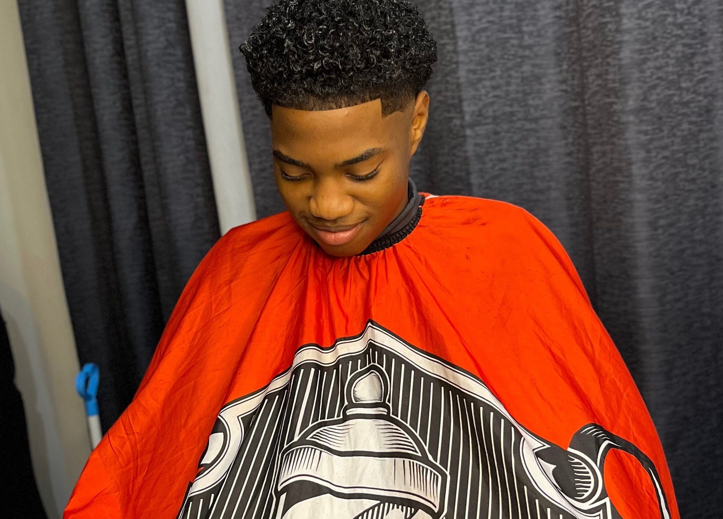 Man receiving haircut at JAYHUNCHO the barber in Paramaribo, Paramaribo, SR with bright red cape.