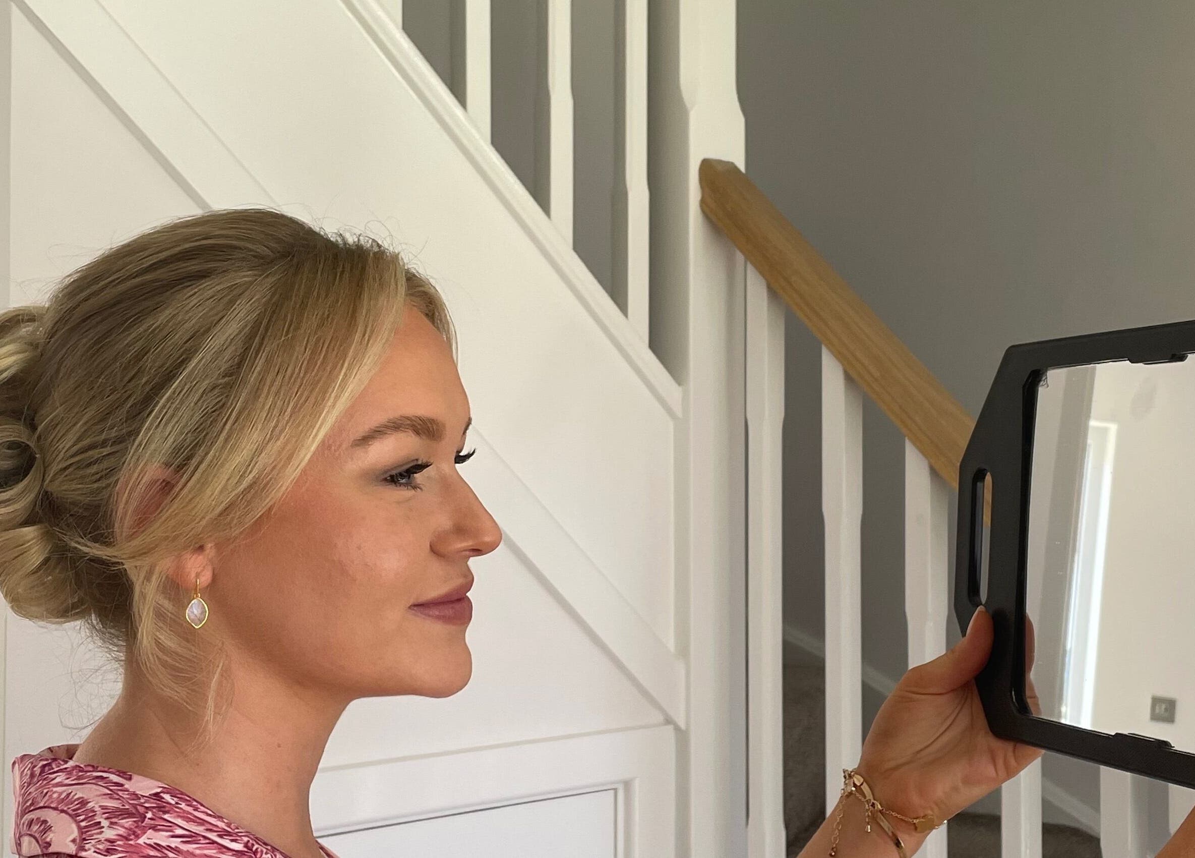 Woman at Josephine's Beauty, Thorrington, England, admiring a stylish updo in a mirror.