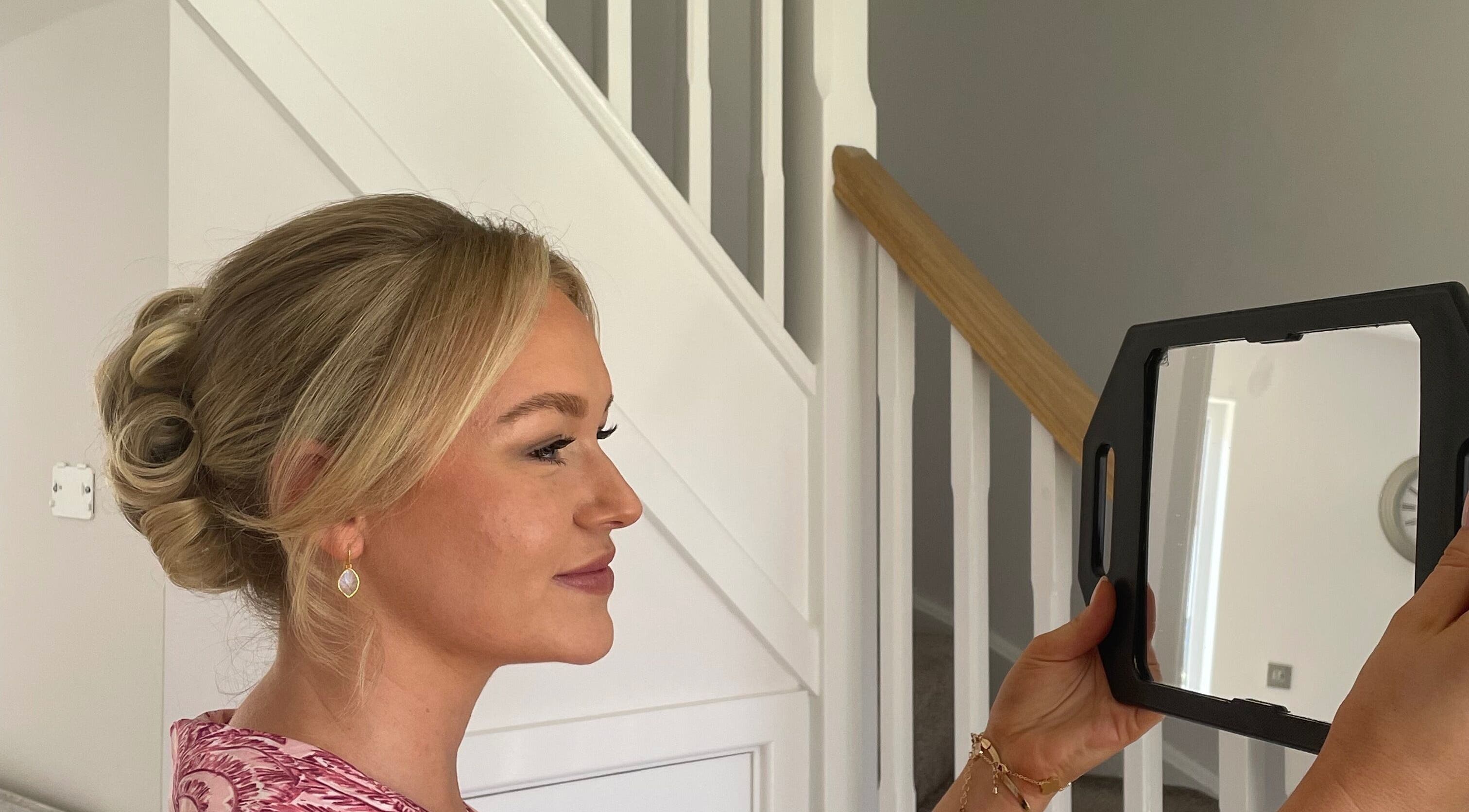 Woman at Josephine's Beauty, Thorrington, England, admiring a stylish updo in a mirror.