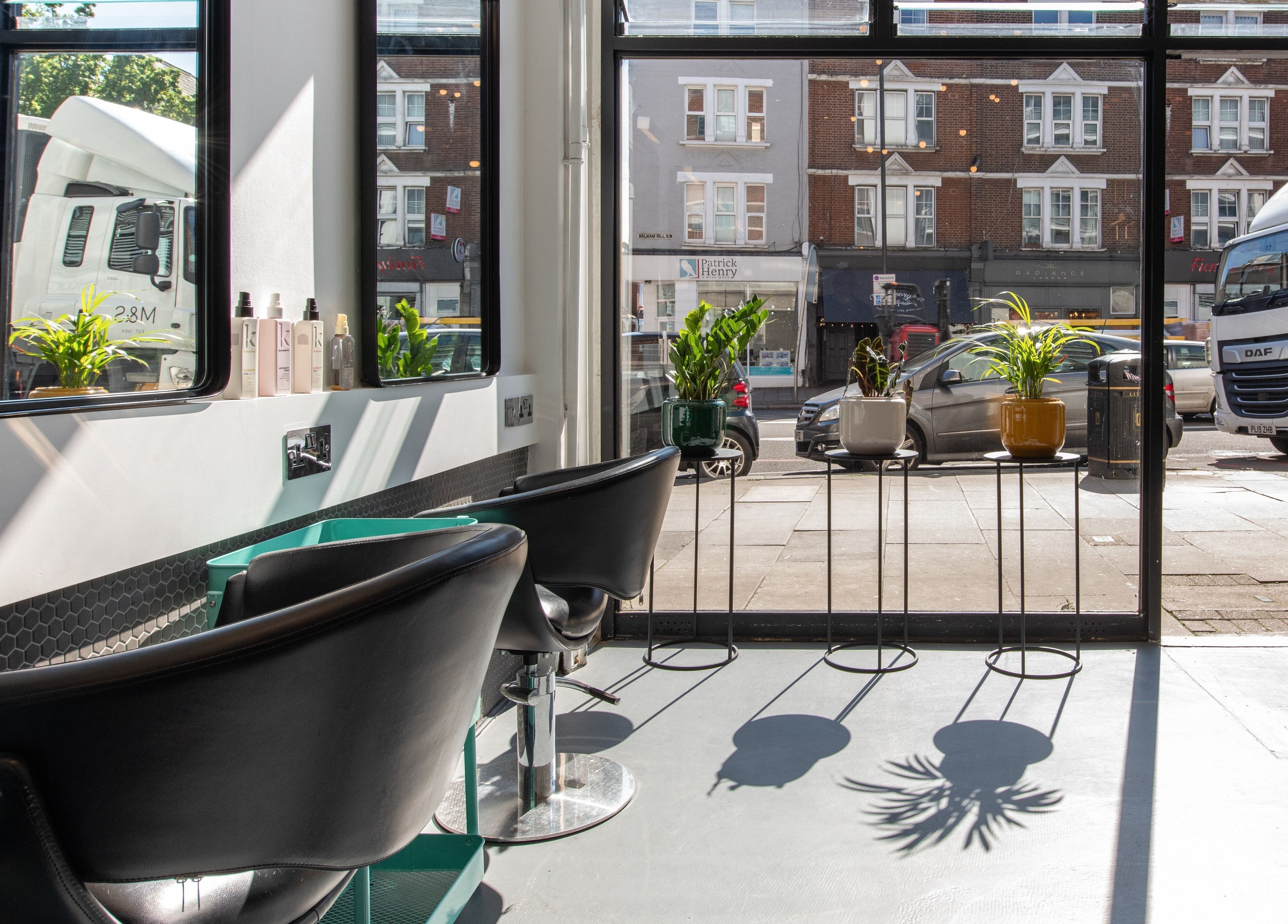 Inside view of Colour Hauz salon in London, England, GB, featuring modern chairs and large windows with street view.