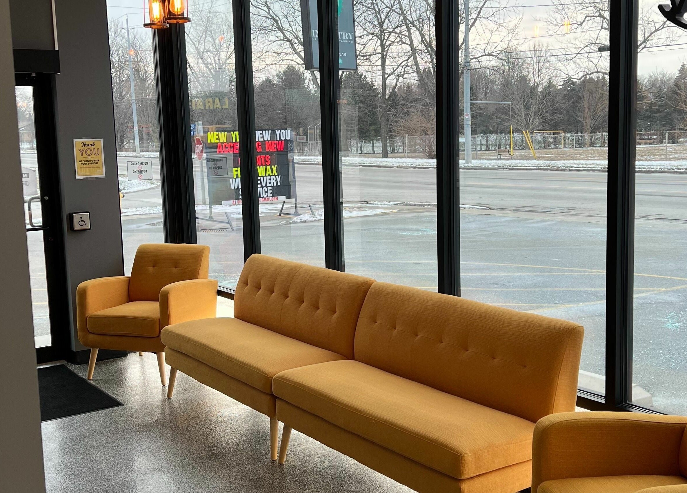 Bright lounge area with orange sofas at Industry Salon and Tanning, Chatham-Kent, Ontario, CA.