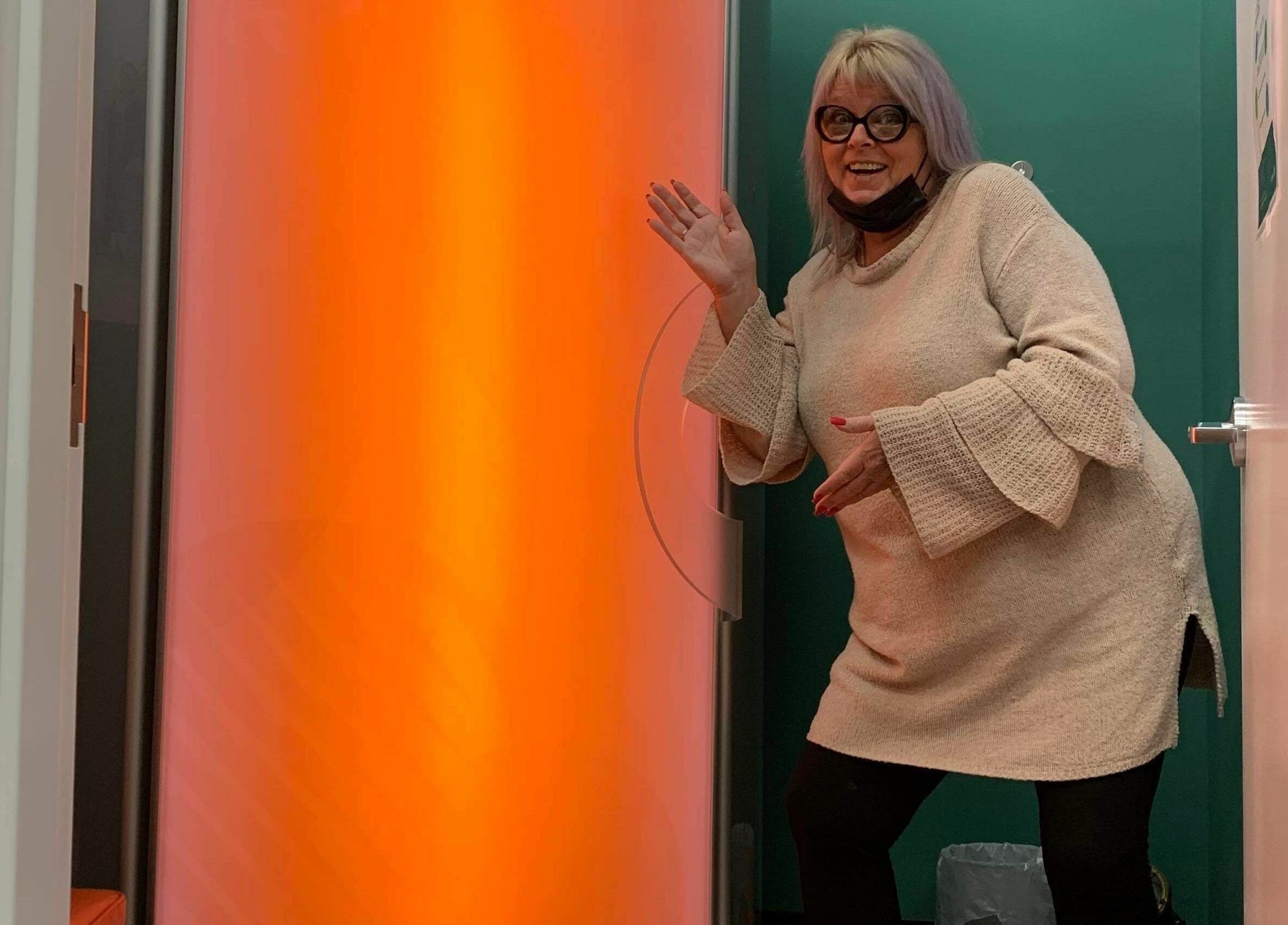 Woman welcoming at orange tanning booth at Industry Salon and Tanning, Chatham-Kent, Ontario, CA.