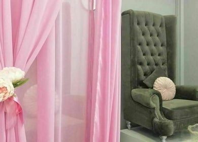 Luxurious seating area at Flawless Face and Beauty Wellington, Wellington, NZ, featuring pink drapes and green chair.