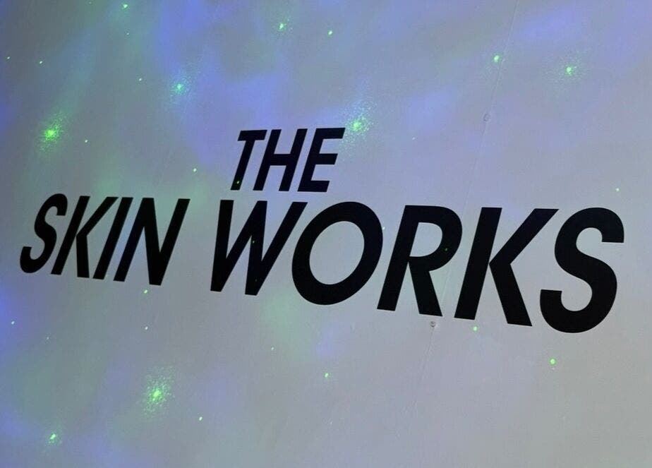 'The Skin Works' logo on a glowing wall at Saint Helens, England, GB venue.