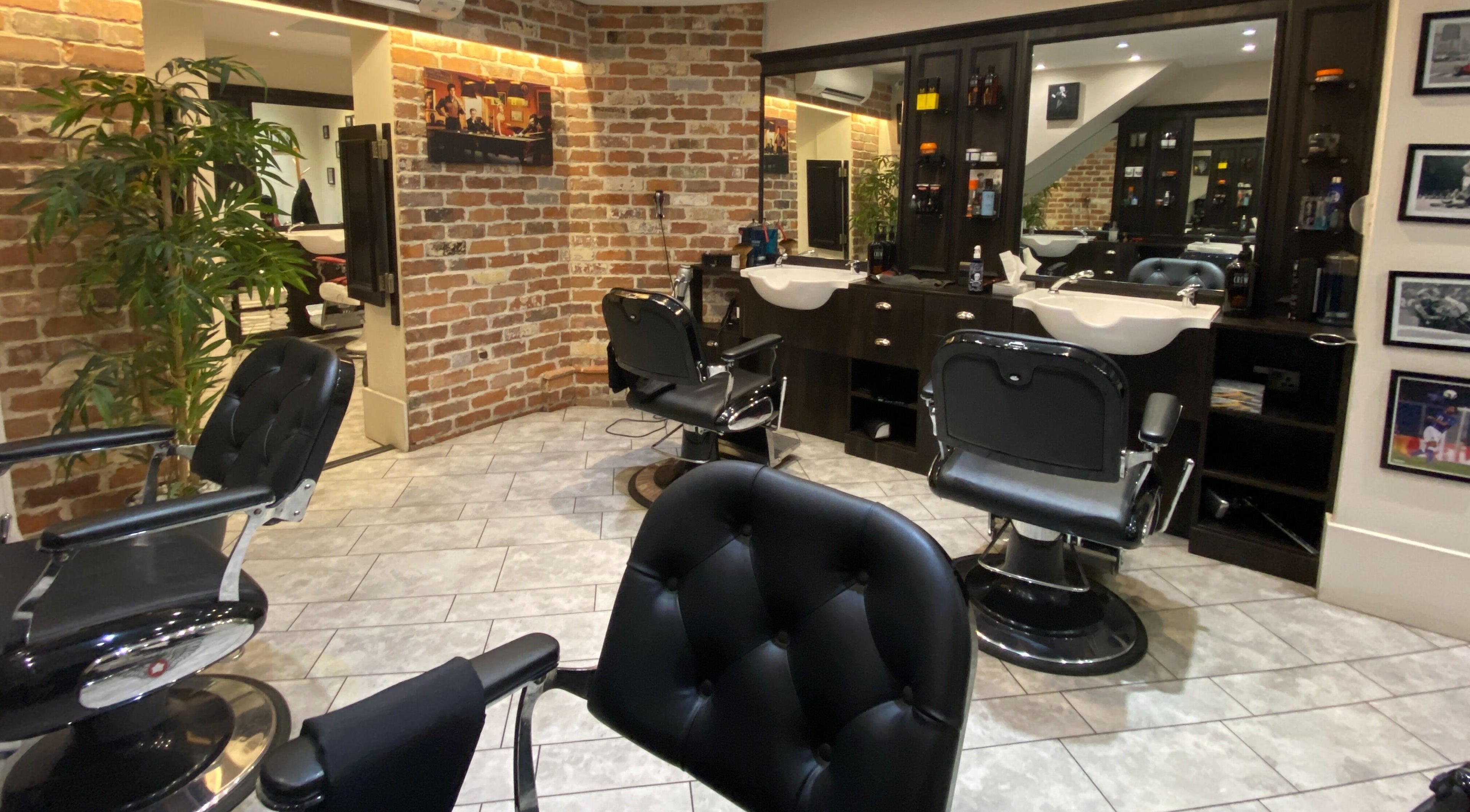 Interior of City and Central Barber Shop, London, England, GB featuring stylish barber chairs and brick walls.