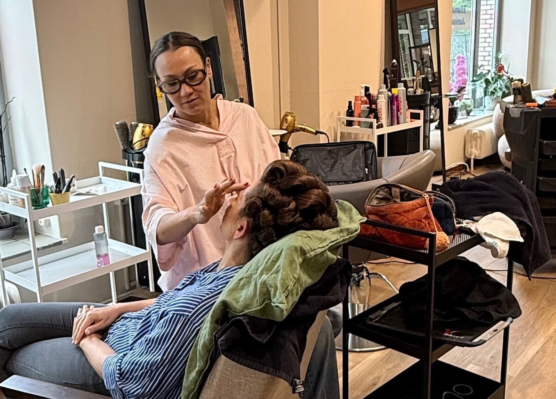 Makeup artist at Eliana Martt, Eindhoven, Noord-brabant, NL applying makeup to a reclining client.