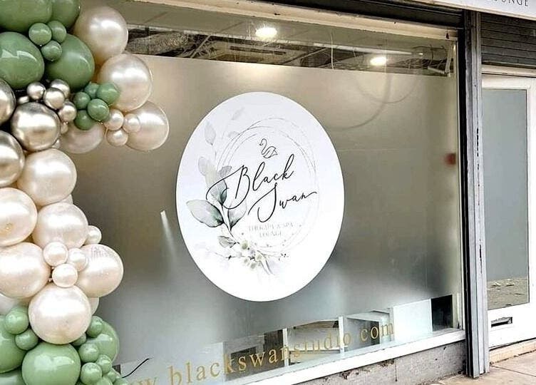 Front window of Black Swan Therapy & Spa Lounge in Bognor Regis, England, GB, adorned with decorative balloons.