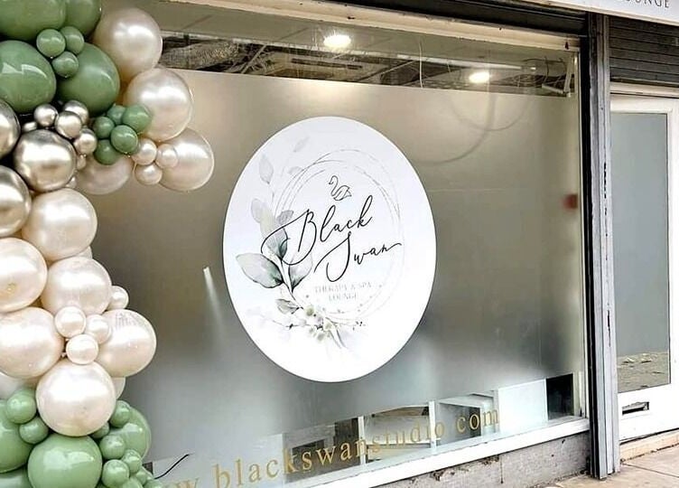 Front window of Black Swan Therapy & Spa Lounge in Bognor Regis, England, GB, adorned with decorative balloons.