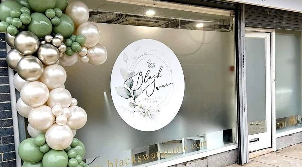 Front window of Black Swan Therapy & Spa Lounge in Bognor Regis, England, GB, adorned with decorative balloons.