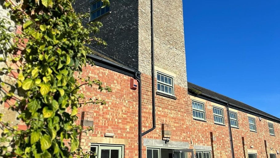 Charming brick exterior of Glow Spray Tanning in Bicester, England, GB, under clear blue skies.