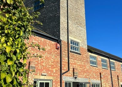 Charming brick exterior of Glow Spray Tanning in Bicester, England, GB, under clear blue skies.