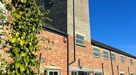 Charming brick exterior of Glow Spray Tanning in Bicester, England, GB, under clear blue skies.