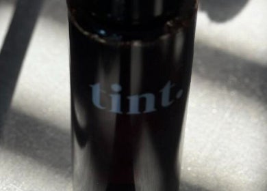 A sleek black bottle labeled 'tint' at Glow Spray Tanning, Bicester, England, GB.