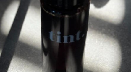 A sleek black bottle labeled 'tint' at Glow Spray Tanning, Bicester, England, GB.