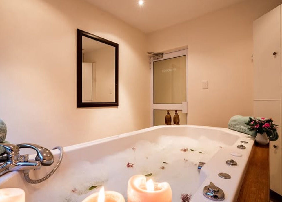 Luxurious bathtub at Total Concept Salon & Spa, Gqeberha, Eastern Cape, ZA, with lit candles and plush towels.