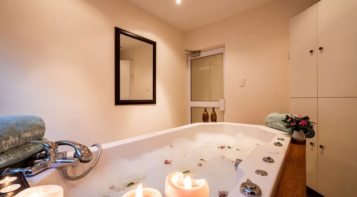 Luxurious bathtub at Total Concept Salon & Spa, Gqeberha, Eastern Cape, ZA, with lit candles and plush towels.