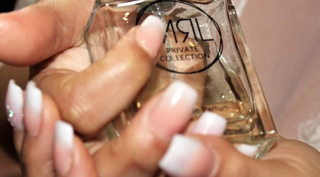 Manicured hands holding a perfume bottle at Nail Craft by Crystal, Cape Town, Western Cape, ZA.