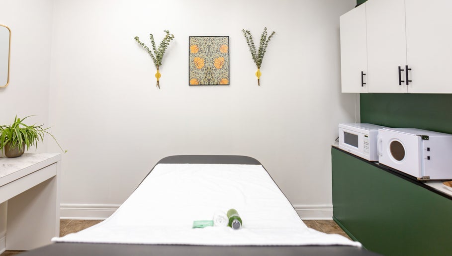 Relaxing massage room at The Pampered Peach, Thorold, Ontario, CA. Features a green accent wall and white decor.