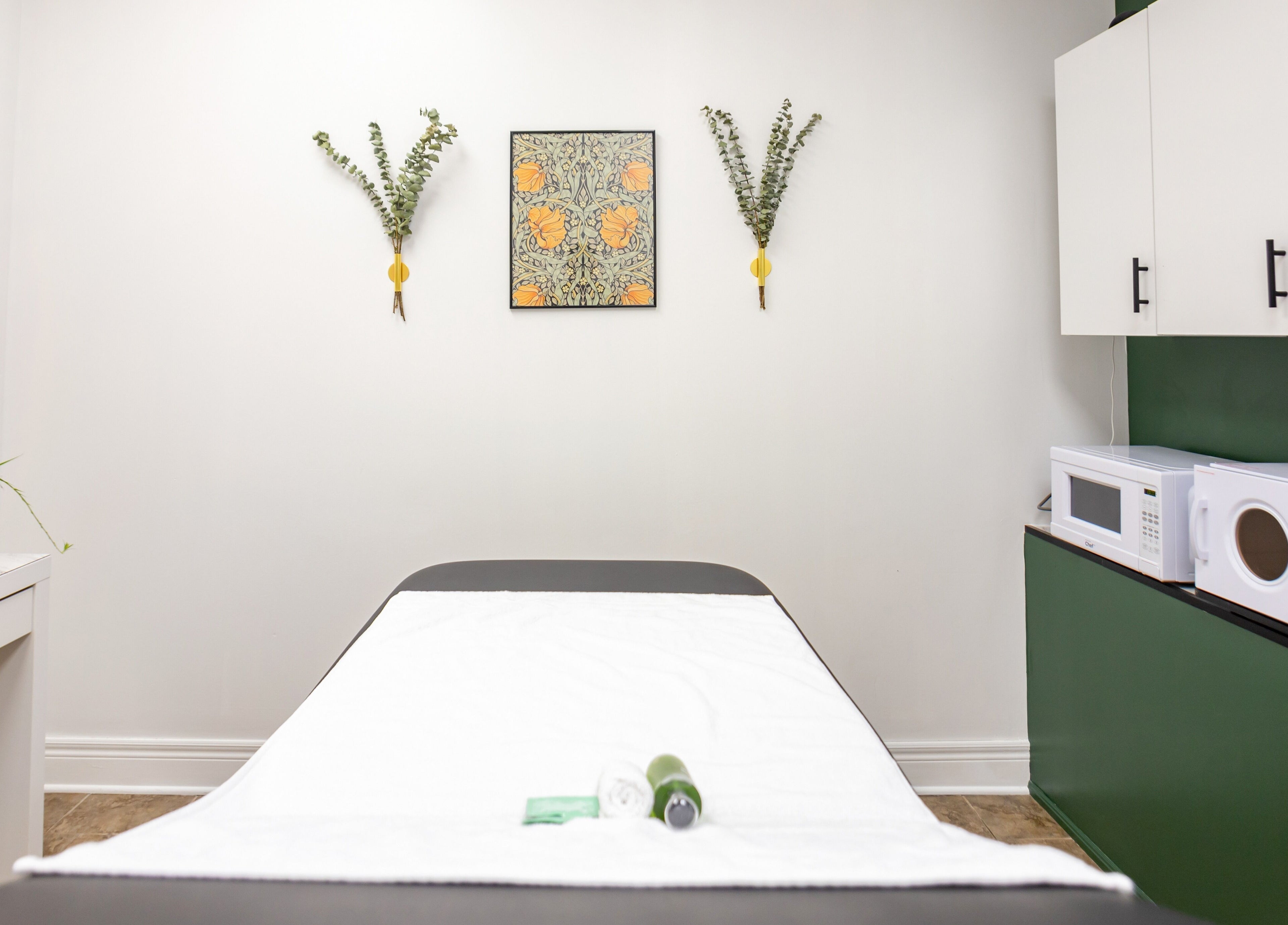 Relaxing massage room at The Pampered Peach, Thorold, Ontario, CA. Features a green accent wall and white decor.