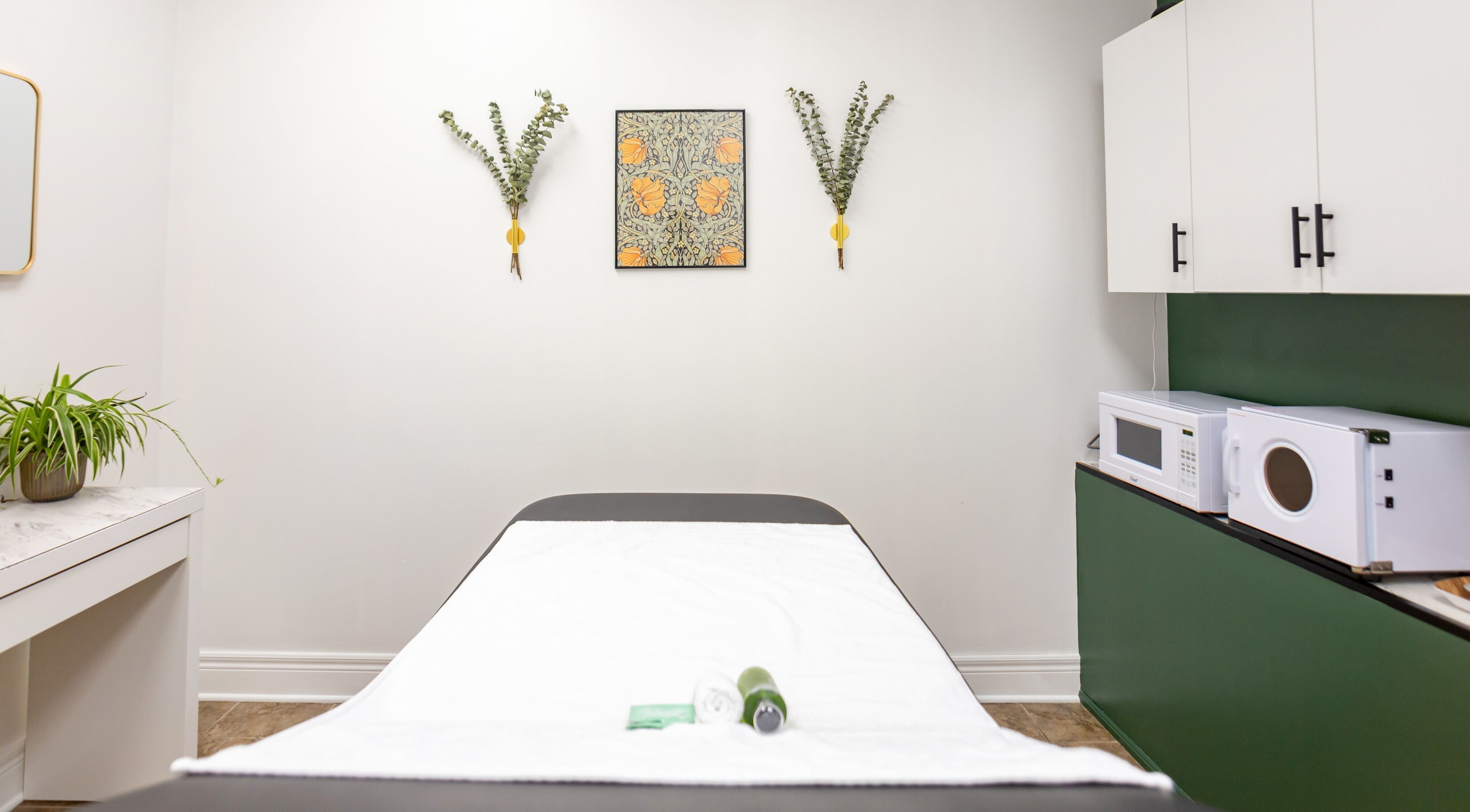 Relaxing massage room at The Pampered Peach, Thorold, Ontario, CA. Features a green accent wall and white decor.