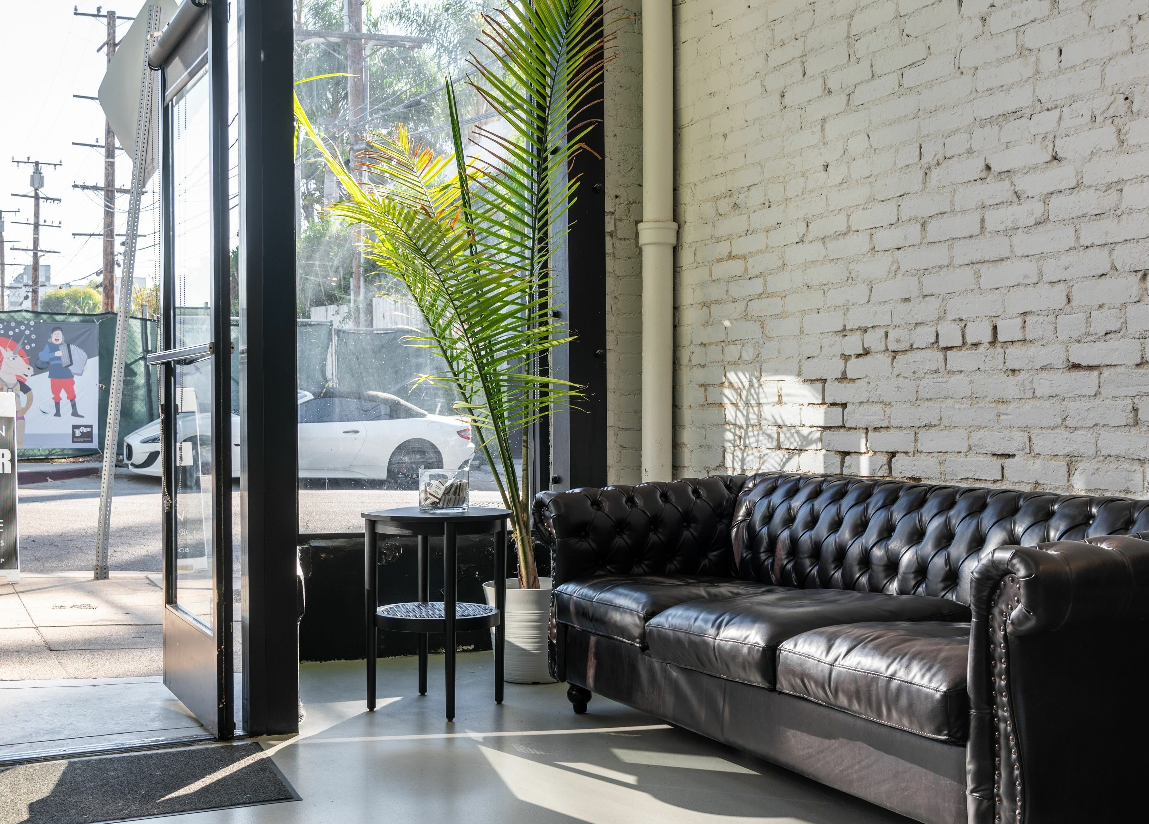 Cozy lounge with leather sofa at Buzzed Barbers West Hollywood, California, US, featuring modern decor and a bright ambiance.