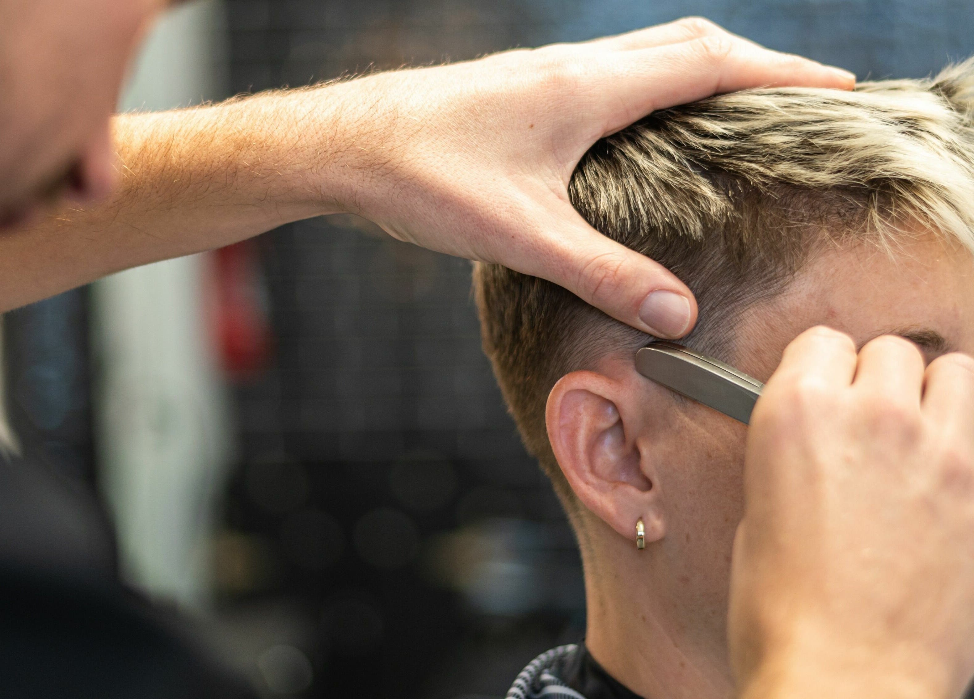 Expert barber at Buzzed Barbers West Hollywood, California, US, styling a modern short haircut.