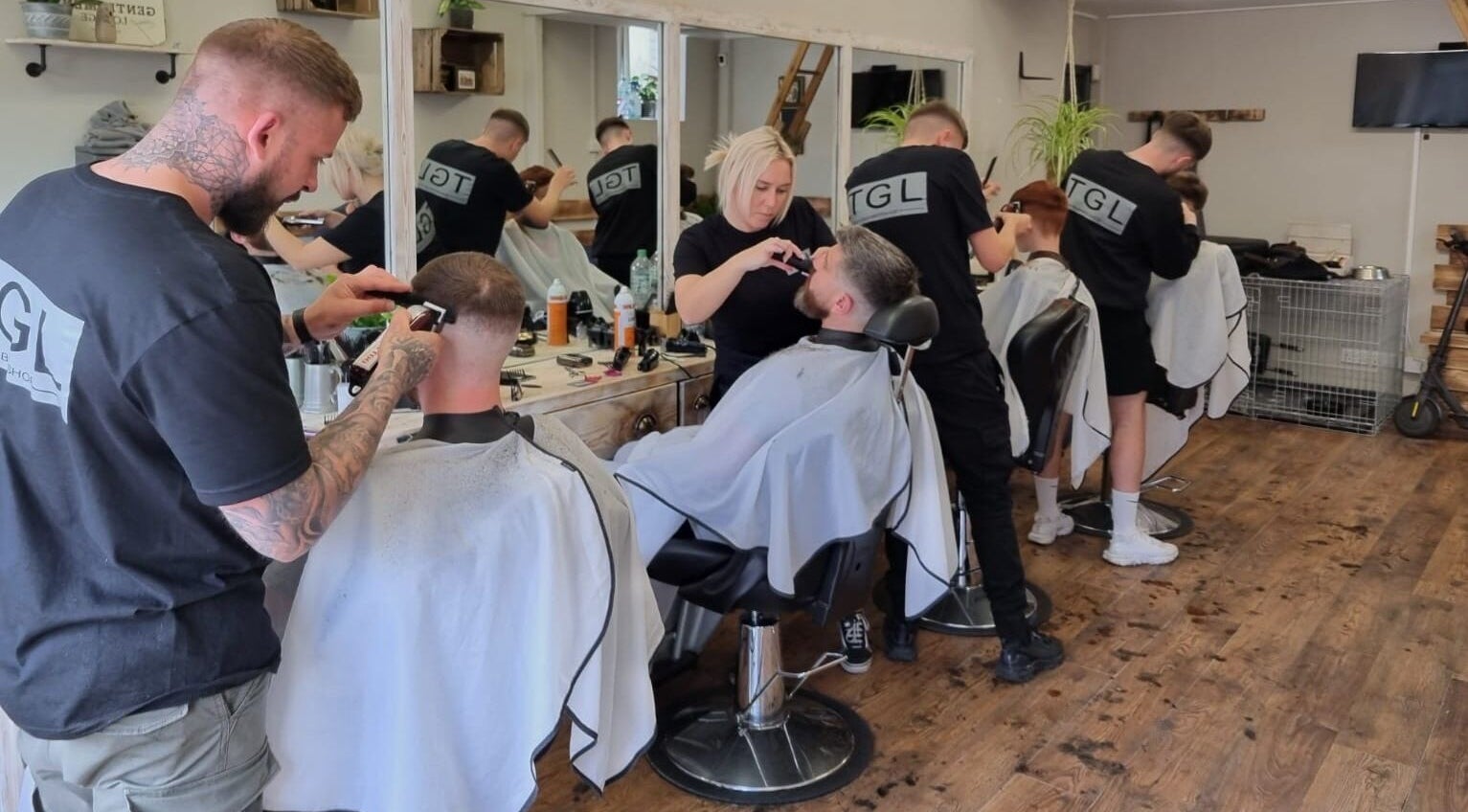 Barbers at work at The Gentlemen’s Lounge Biggleswade, England, GB providing stylish haircuts.