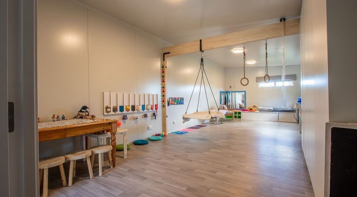 Spacious therapy room at Neurotherapy NZ in Waikanae, Wellington, NZ, featuring a swing and wooden furniture.