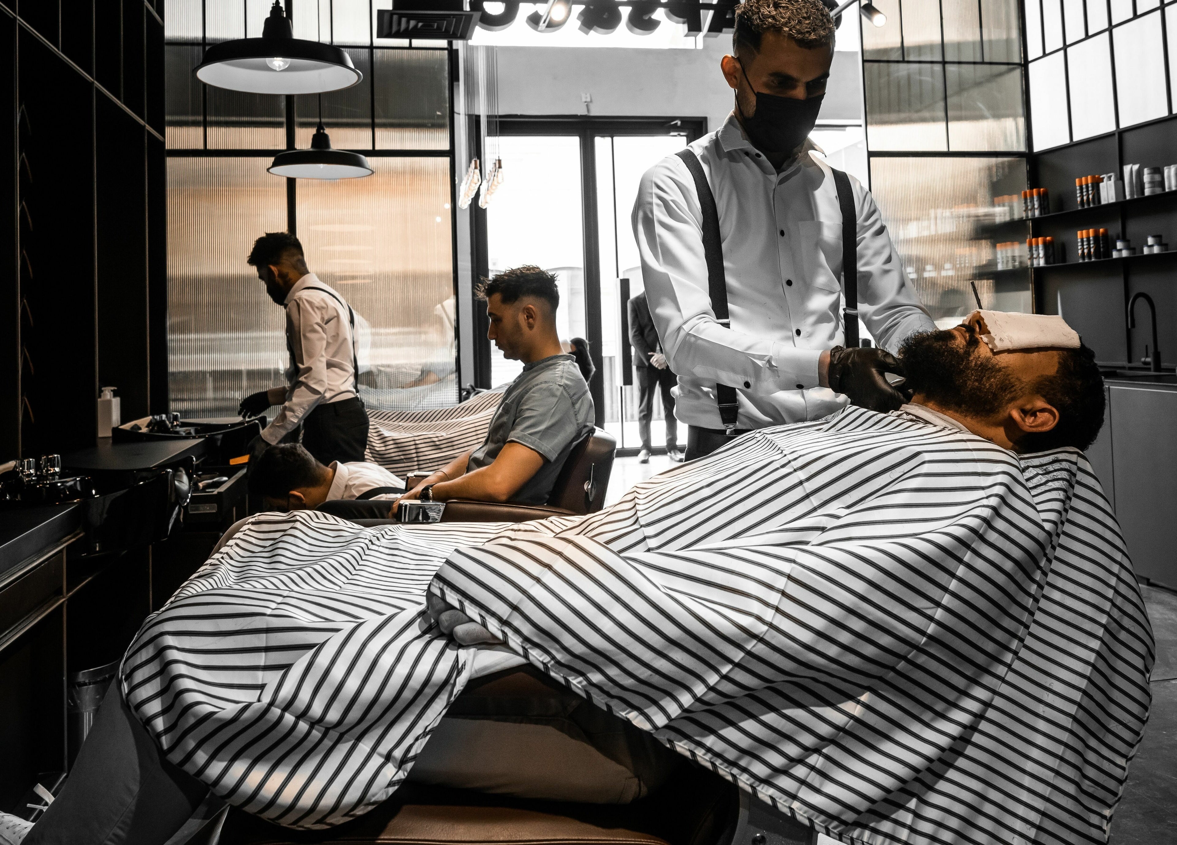 Barber at Chaps & Co - Nojoud Mall, Riyadh, styling a client's beard in a modern setting.