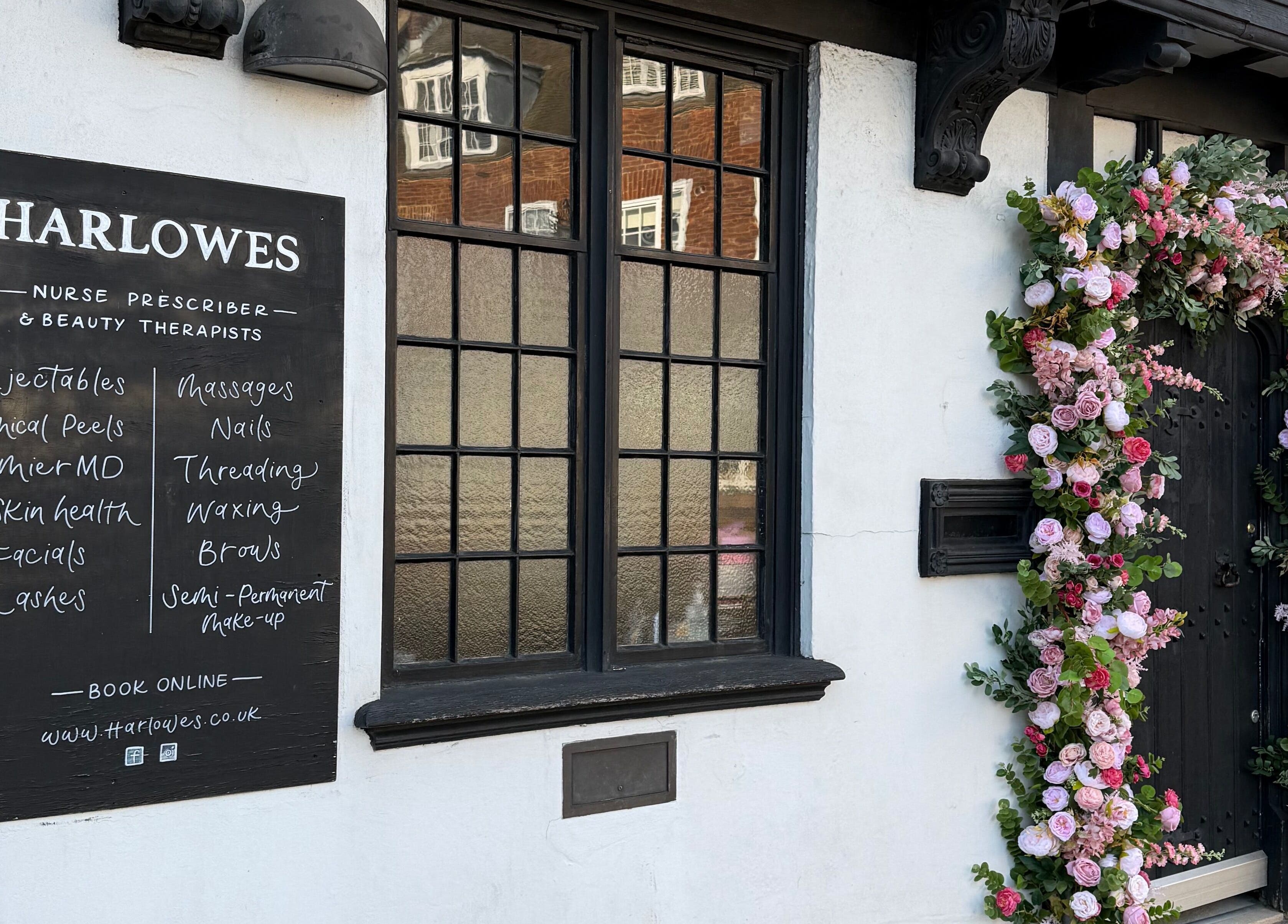 Harlowes & Sophie Rae Medical in Sandwich, England, GB. Elegant exterior with a flower arch and menu board.
