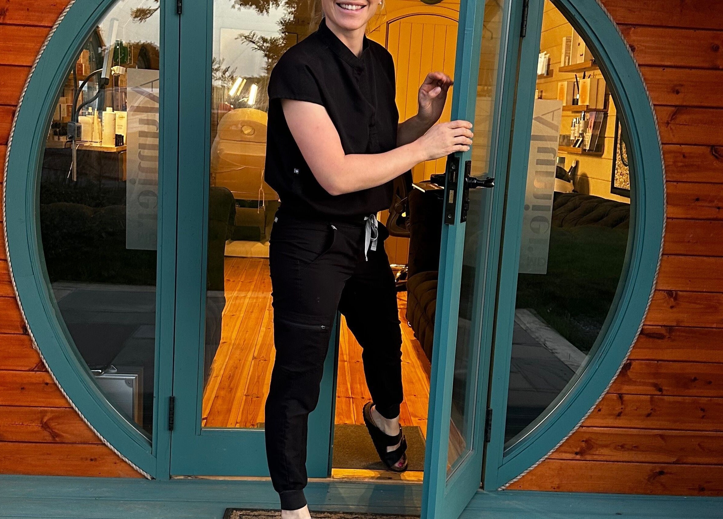 Smiling staff member opens the round green door at Sophie Rae Medical, Dover in Guston, England, GB.
