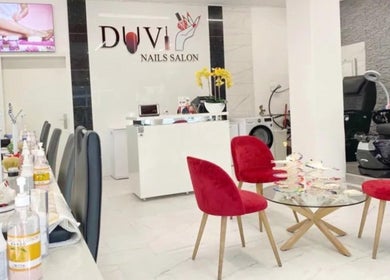 Innenansicht von DUVI Nails Salon in Chur, Graubünden, CH mit modernen roten Stühlen und Nagelarbeitstischen.