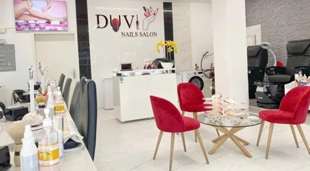 Innenansicht von DUVI Nails Salon in Chur, Graubünden, CH mit modernen roten Stühlen und Nagelarbeitstischen.