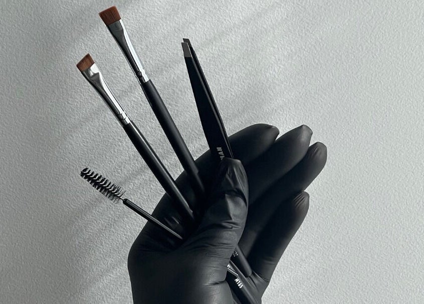 Professional makeup tools held in black-gloved hand at Luxe Pacifique, Byron Bay, New South Wales, AU.
