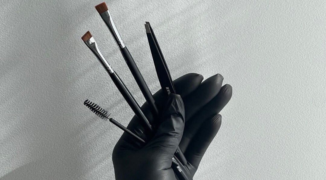 Professional makeup tools held in black-gloved hand at Luxe Pacifique, Byron Bay, New South Wales, AU.
