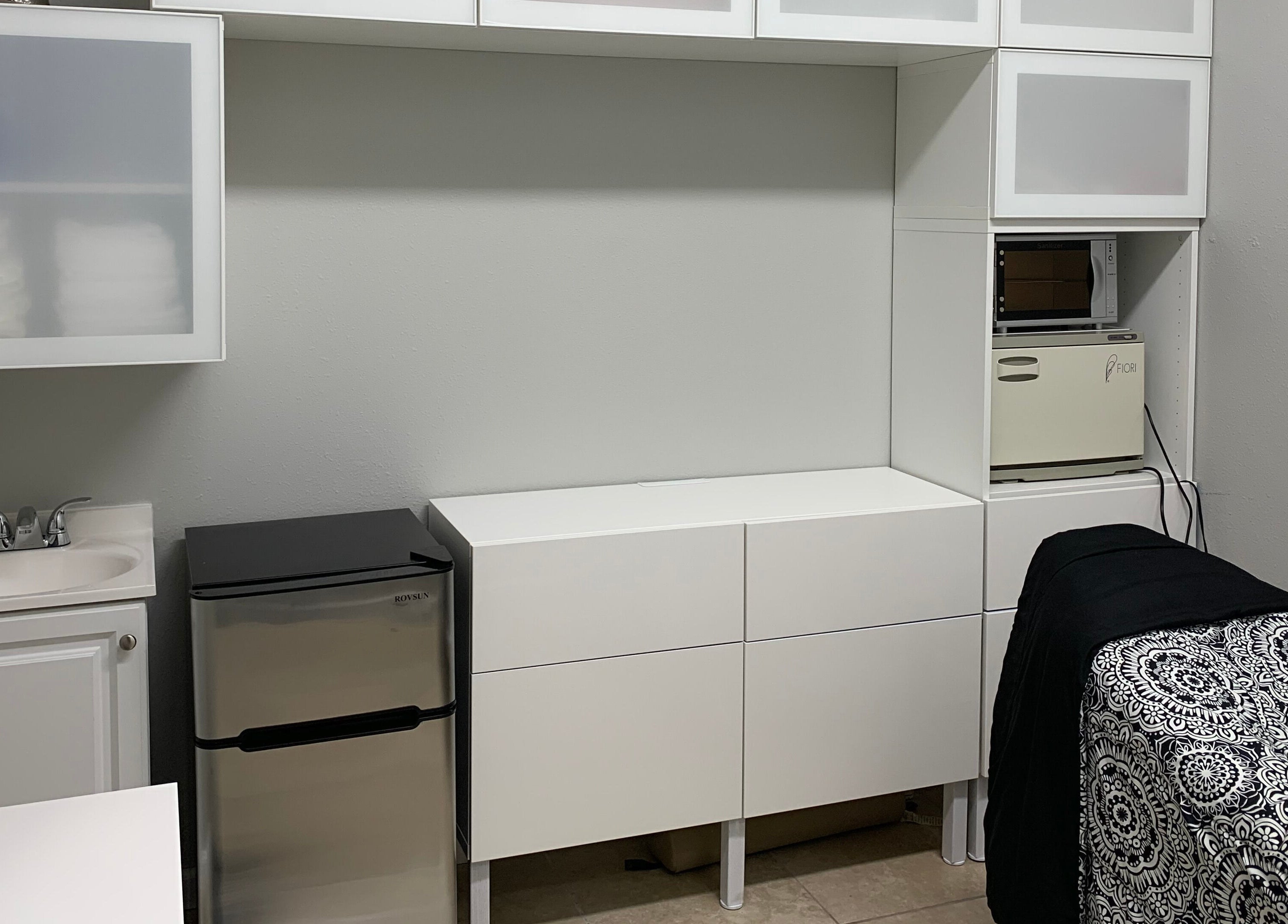 Modern treatment room at Alka's Glo Studio in Helotes, Texas, US with sleek cabinets and patterned bedspread.