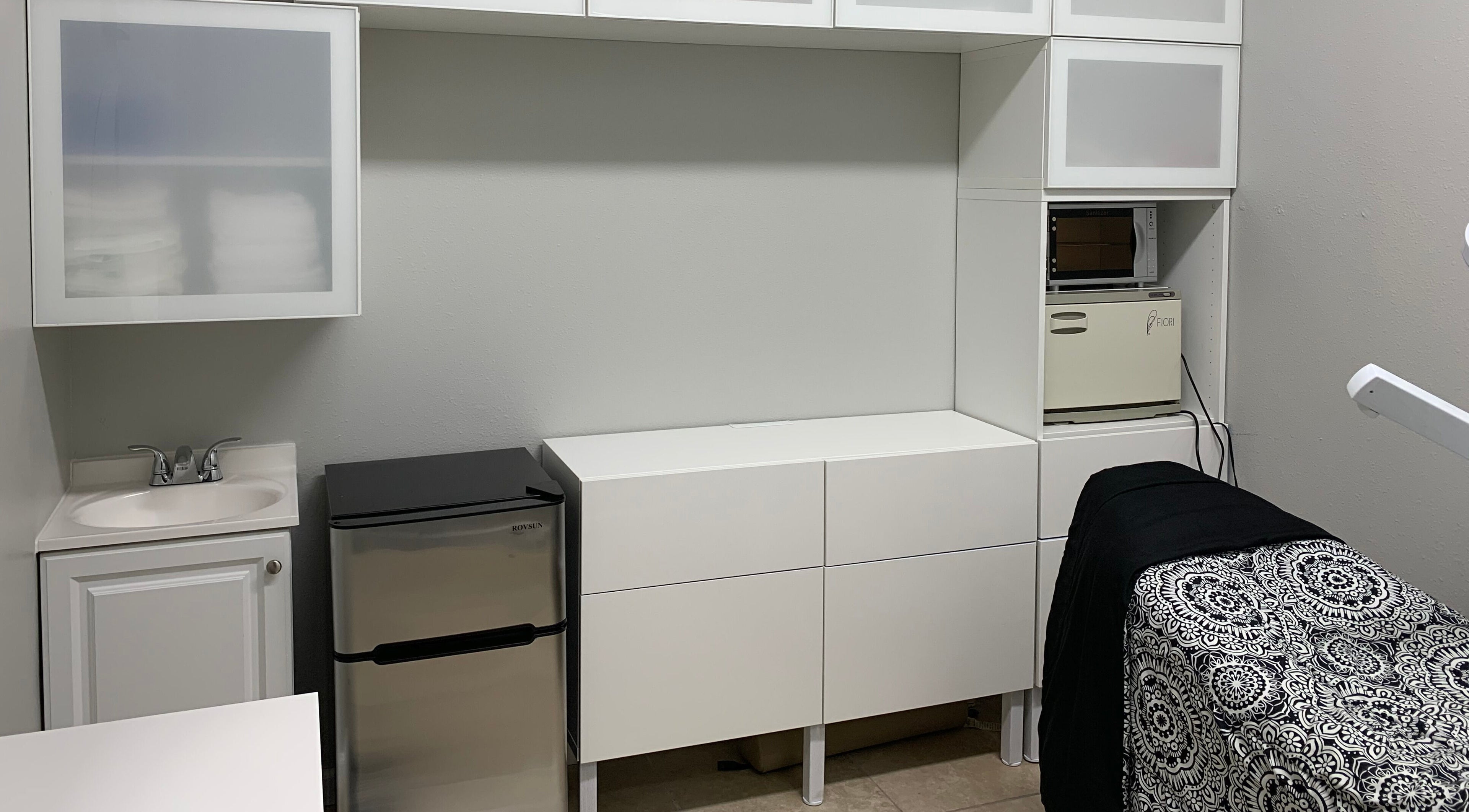 Modern treatment room at Alka's Glo Studio in Helotes, Texas, US with sleek cabinets and patterned bedspread.