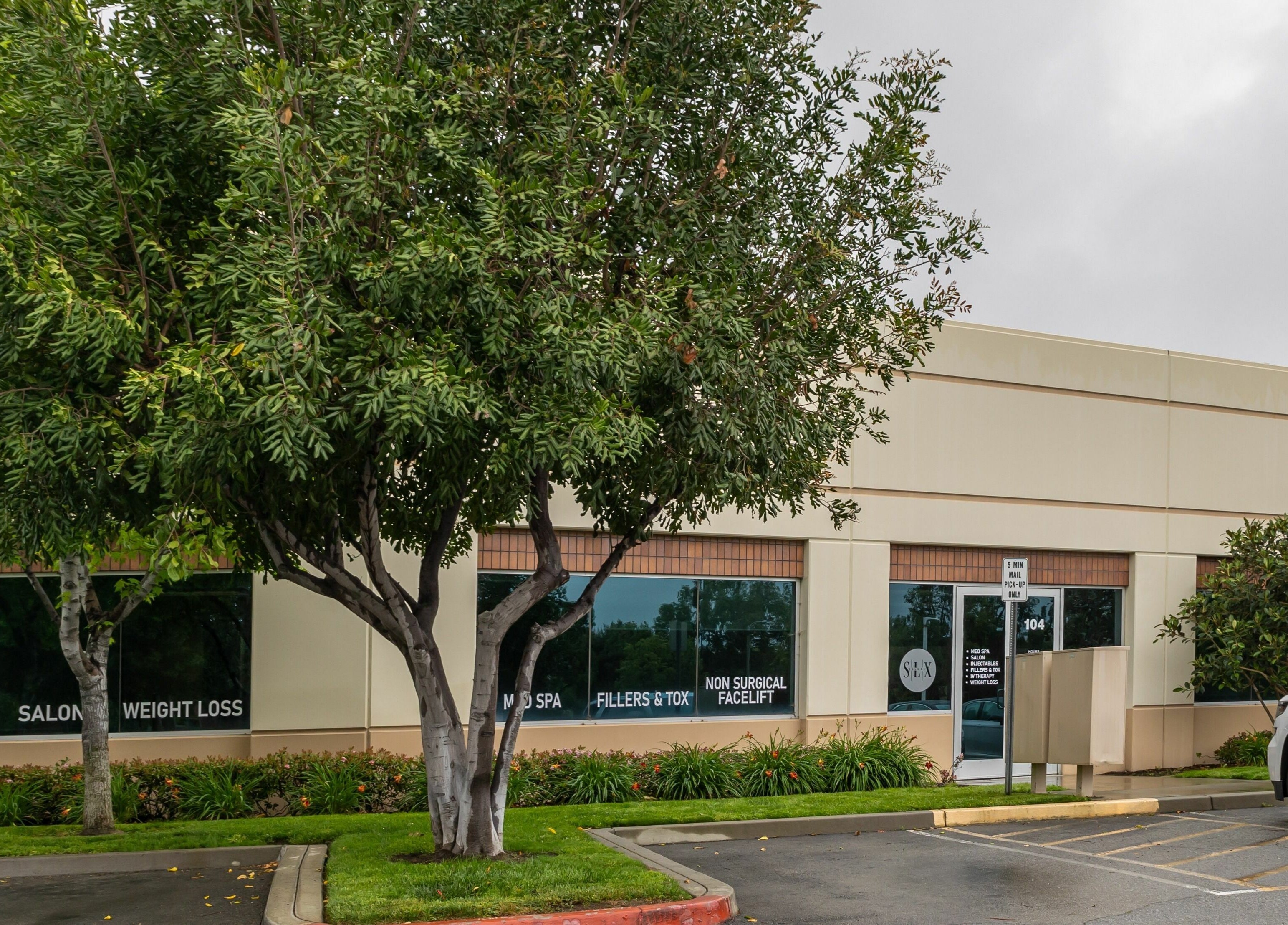 Entrance of So Luxe Med Spa, surrounded by lush trees in Rancho Cucamonga, California, US.