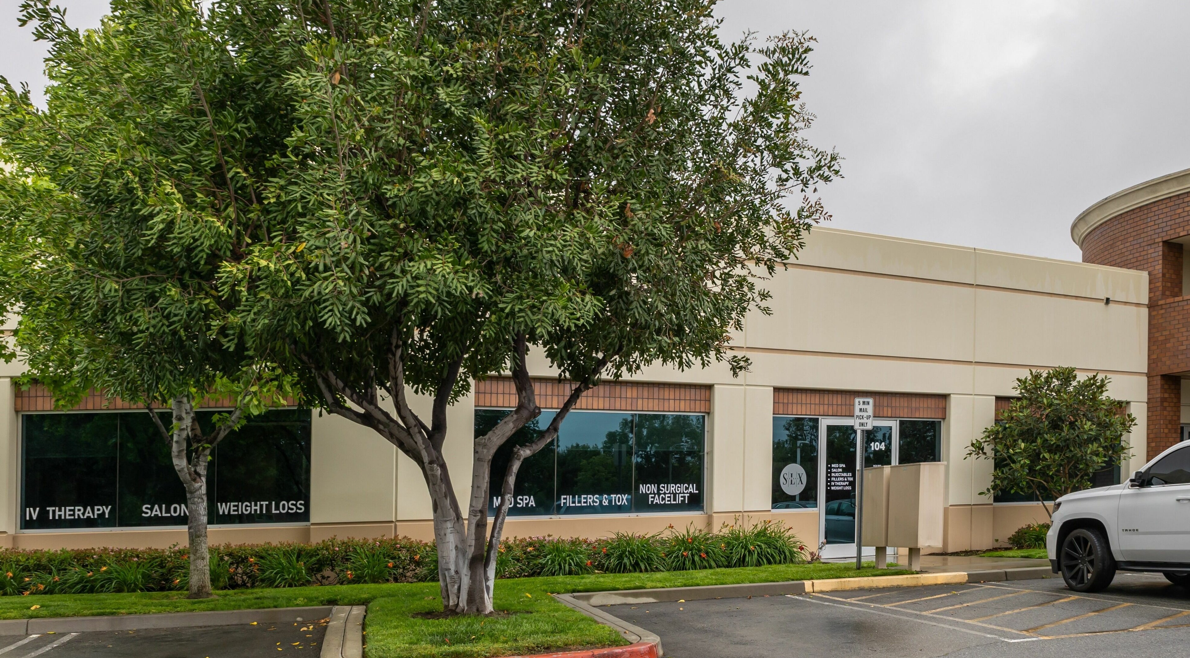 Entrance of So Luxe Med Spa, surrounded by lush trees in Rancho Cucamonga, California, US.