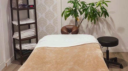 Salle de massage chaleureuse au Studio Orchidée, Montréal, Québec, CA, avec table et plante verte.