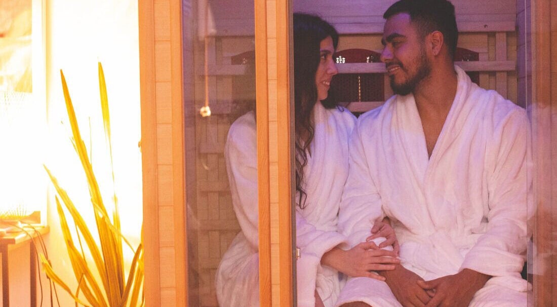 Couple relaxant dans le sauna à Studio Orchidée, Montréal, Québec, CA, en peignoirs blancs.