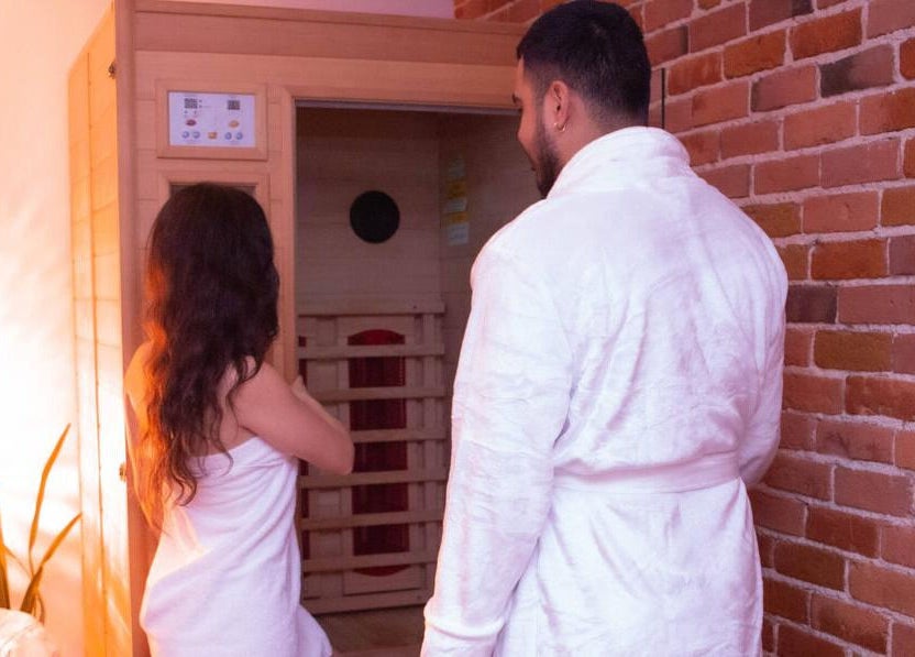 Deux personnes en peignoir à Studio Orchidée, Montréal, Québec, CA, prêtent à entrer dans un sauna chaleureux.