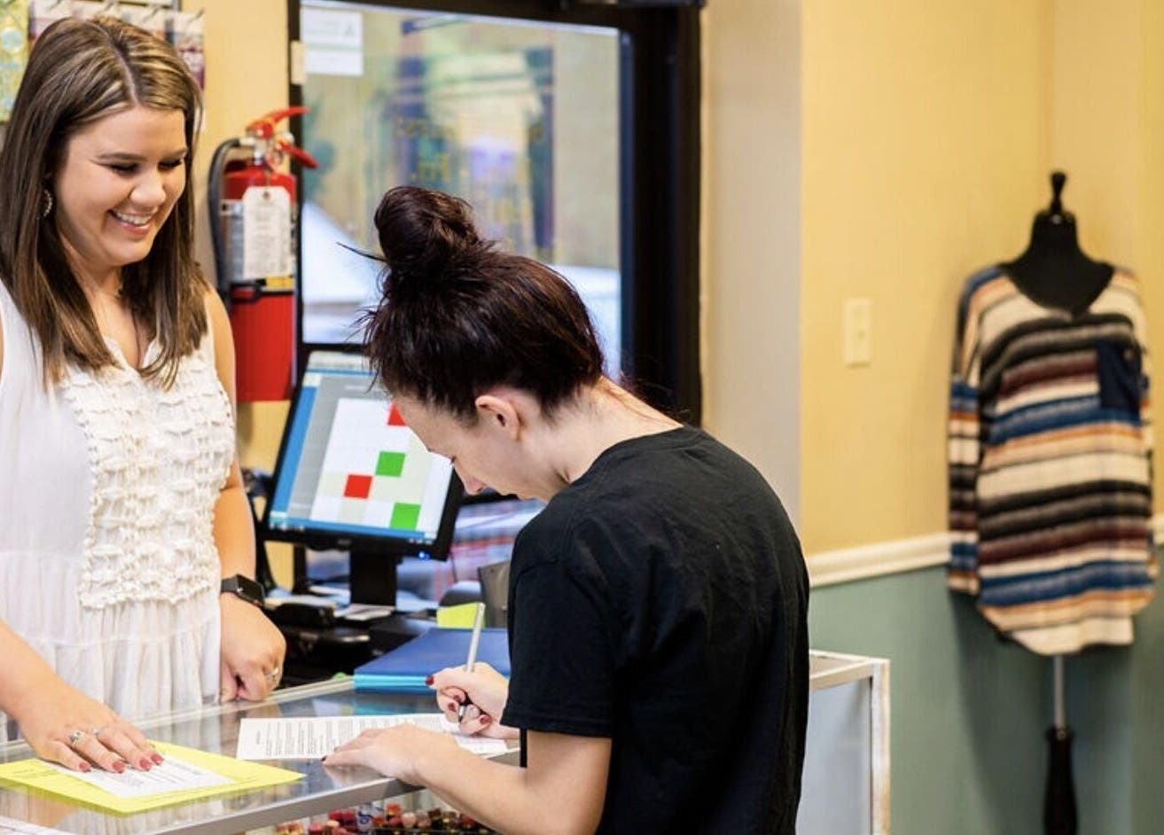 A cheerful interaction at Solar Image checkout counter in Lufkin, Texas, US, enhancing customer service experience.