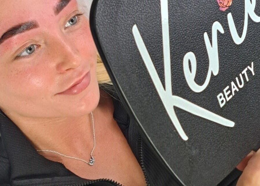 Client admiring brows in Kerie Beauty mirror, Saint Asaph, Wales, GB, showcasing stunning results.