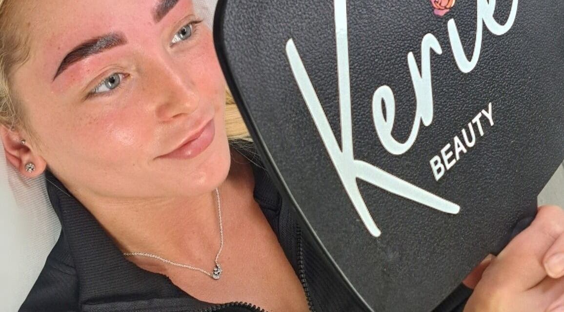 Client admiring brows in Kerie Beauty mirror, Saint Asaph, Wales, GB, showcasing stunning results.