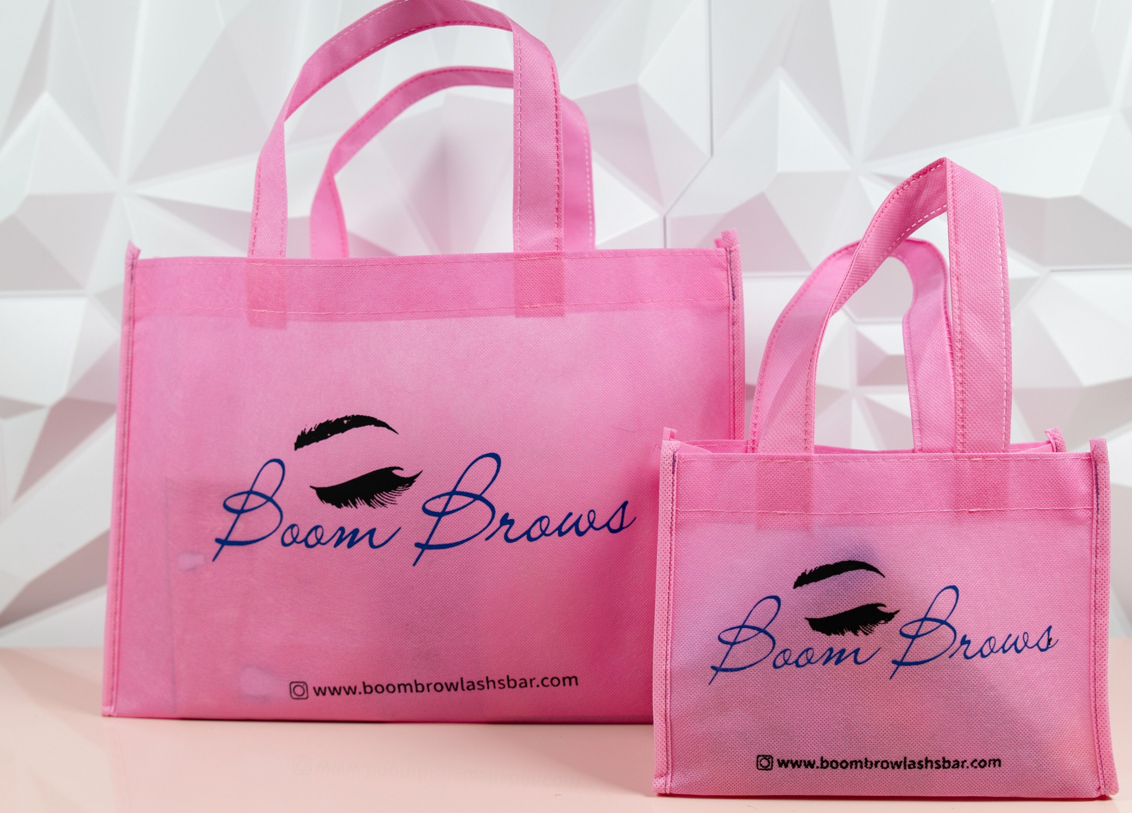 Pink branded totes at Boom Brows Lash Bar and More, Farmingdale, New York, US showcasing elegant beauty.