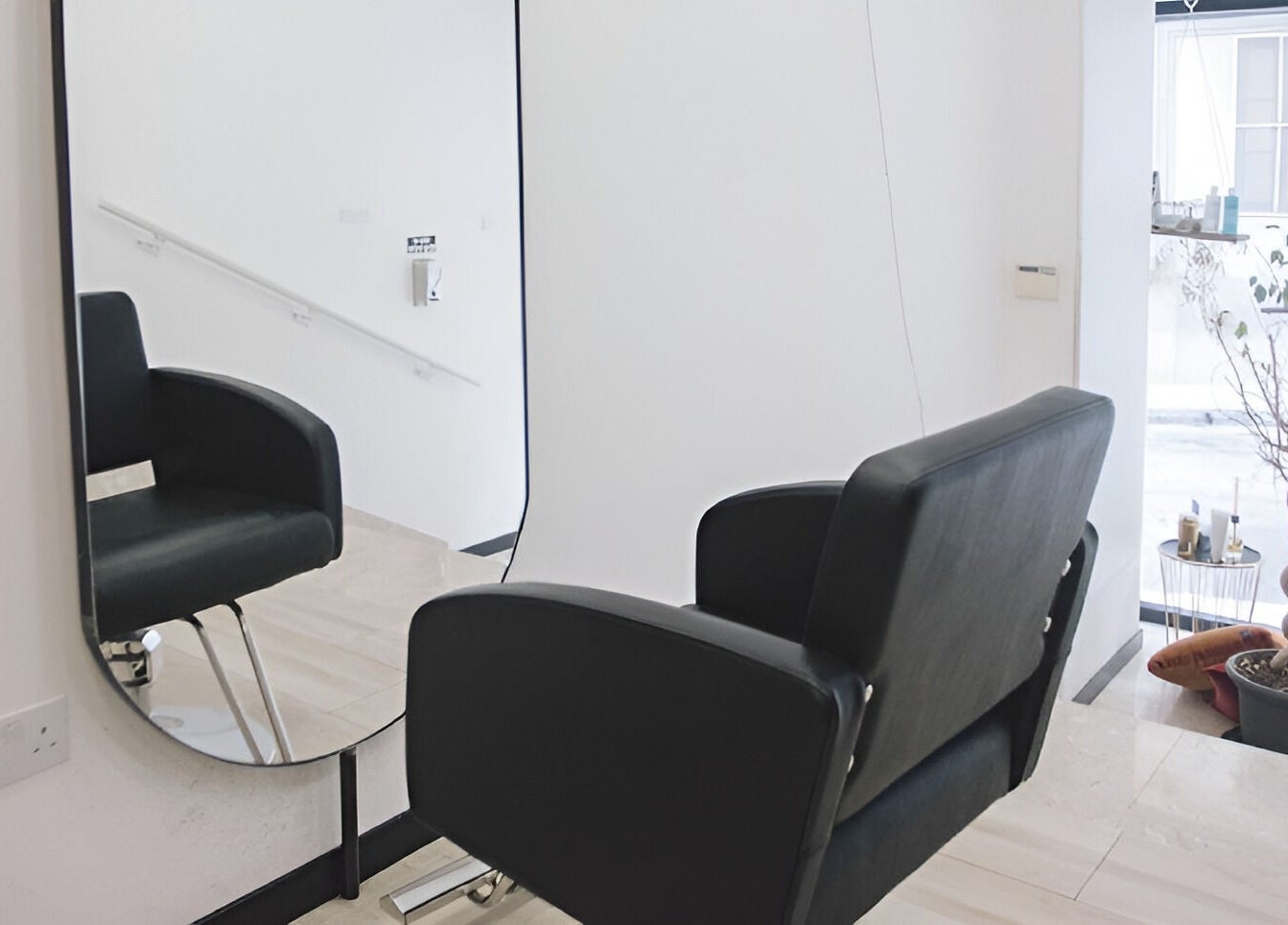 Modern salon chair and mirror at Elena Salon Sliema, Sliema, MT, showcasing sleek interior design.