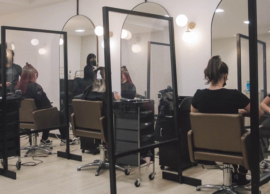 Interior of Elena Salon Sliema in Sliema, MT, showcasing stylish mirrored stations with clients and stylists.