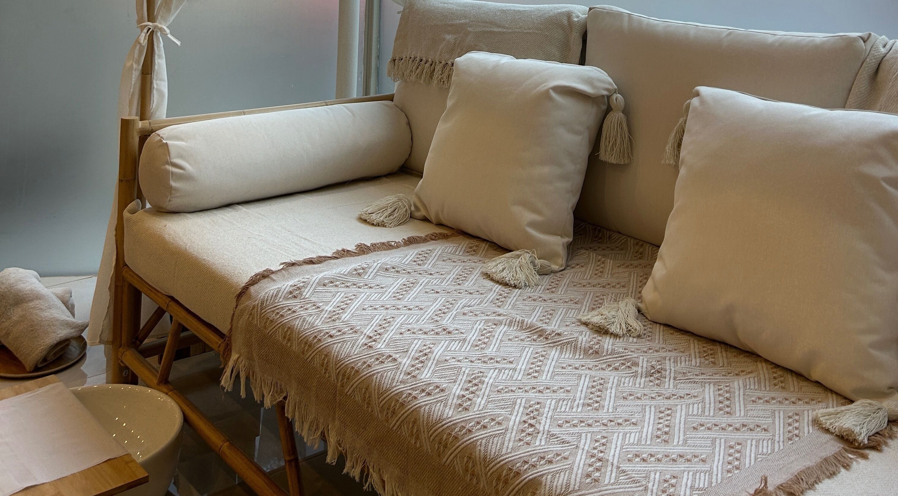 Elegant seating area at Ellie Glover Beauty, Lowestoft, England, GB, with plush pillows and textured throws.