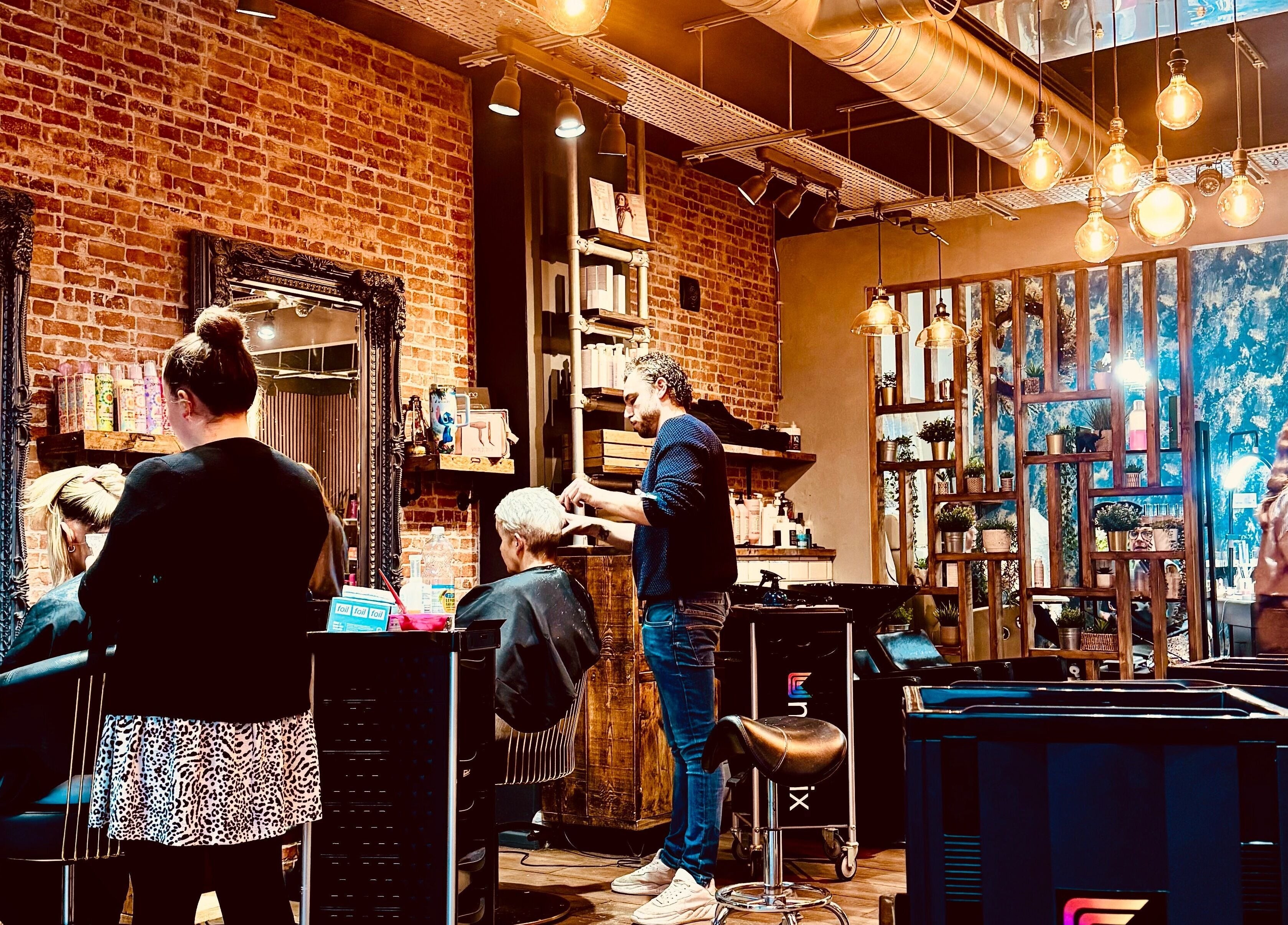 Stylists at work in Glam Factory hair salon, Nuneaton, England, GB, featuring exposed brick and modern decor.